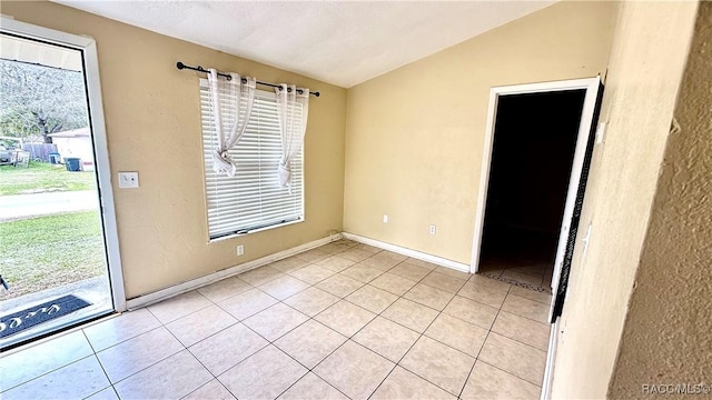 empty room featuring light tile patterned floors, lofted ceiling, and plenty of natural light