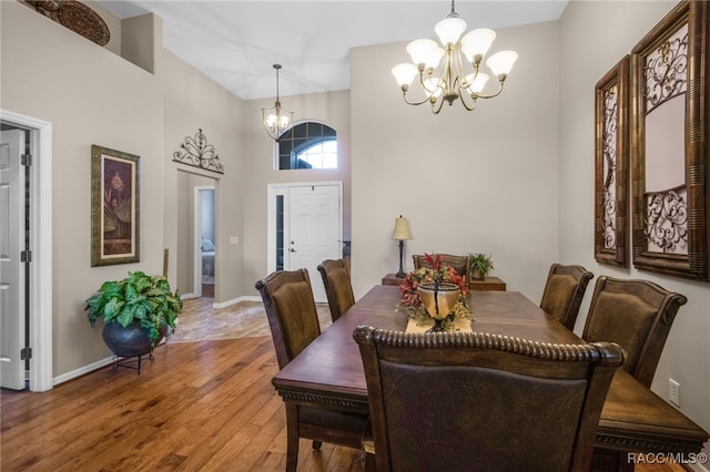 dining space featuring an inviting chandelier, hardwood / wood-style floors, and a high ceiling