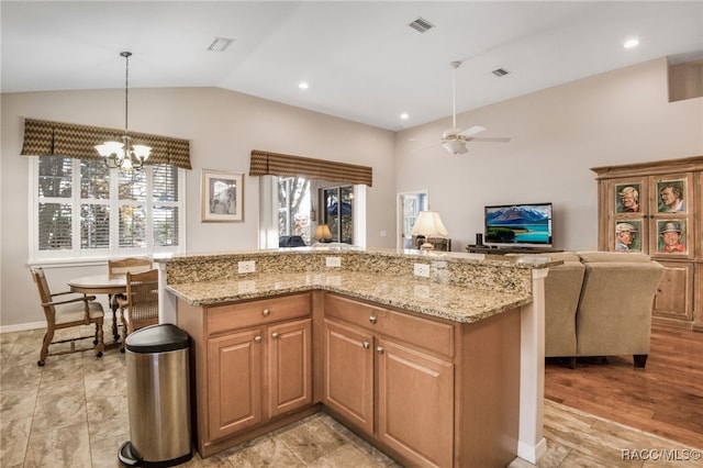 kitchen with pendant lighting, light stone counters, a kitchen island, ceiling fan with notable chandelier, and vaulted ceiling