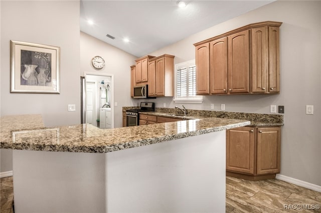 kitchen featuring lofted ceiling, sink, light stone counters, and appliances with stainless steel finishes