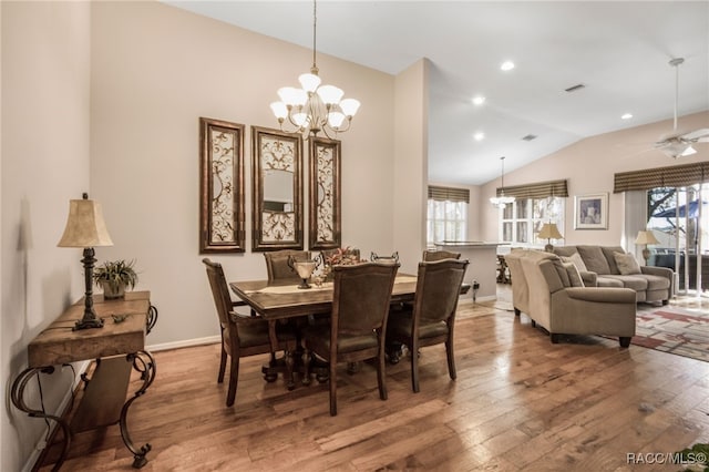 dining space with wood-type flooring, vaulted ceiling, and ceiling fan with notable chandelier