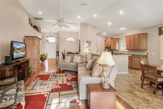 living room featuring lofted ceiling, sink, ceiling fan with notable chandelier, and light hardwood / wood-style flooring