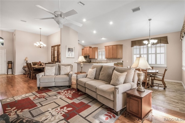 living room with dark wood-type flooring, ceiling fan with notable chandelier, and high vaulted ceiling