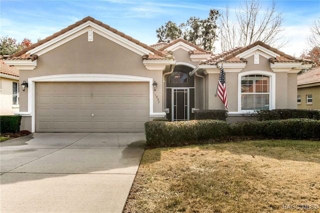 mediterranean / spanish home with a garage and a front lawn