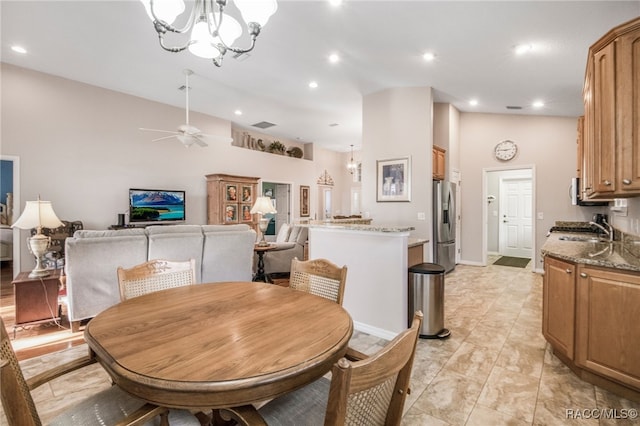 dining area featuring sink, ceiling fan with notable chandelier, and vaulted ceiling