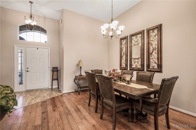 dining room with a towering ceiling, wood-type flooring, and a notable chandelier