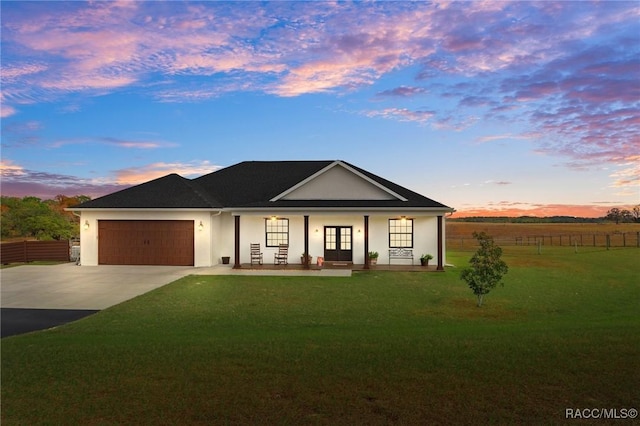 view of front of house featuring a lawn, a porch, and a garage