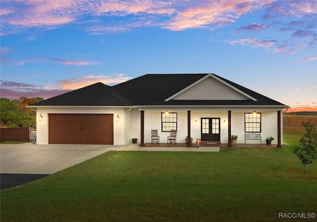 view of front facade with french doors, a porch, a garage, and a lawn