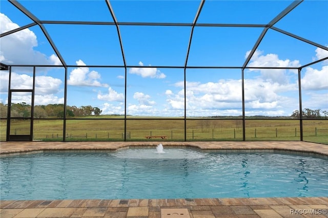 view of swimming pool featuring a lawn, pool water feature, a rural view, and a lanai