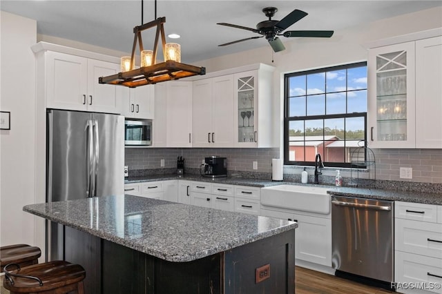 kitchen with backsplash, appliances with stainless steel finishes, decorative light fixtures, a kitchen bar, and white cabinetry