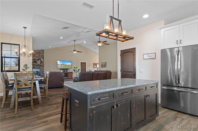 kitchen with pendant lighting, a center island, white cabinets, dark hardwood / wood-style floors, and stainless steel fridge