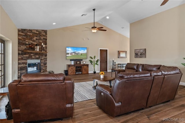 living room with ceiling fan, lofted ceiling, and a fireplace