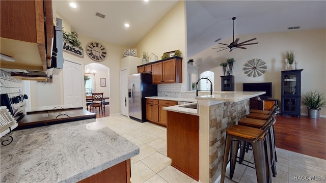 kitchen featuring sink, light hardwood / wood-style flooring, stainless steel refrigerator with ice dispenser, stove, and a breakfast bar area