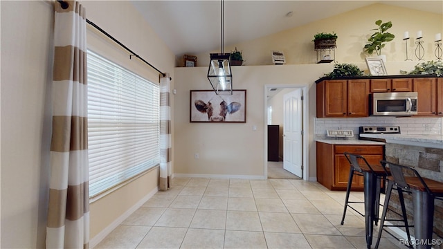 kitchen with decorative backsplash, light tile patterned floors, hanging light fixtures, and lofted ceiling