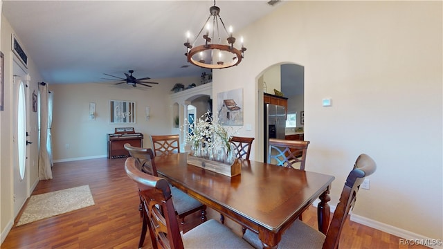 dining space featuring ceiling fan with notable chandelier, hardwood / wood-style flooring, and lofted ceiling