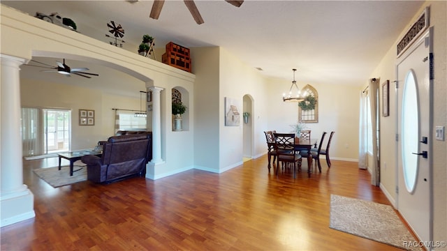 dining area with ornate columns, wood-type flooring, and ceiling fan with notable chandelier