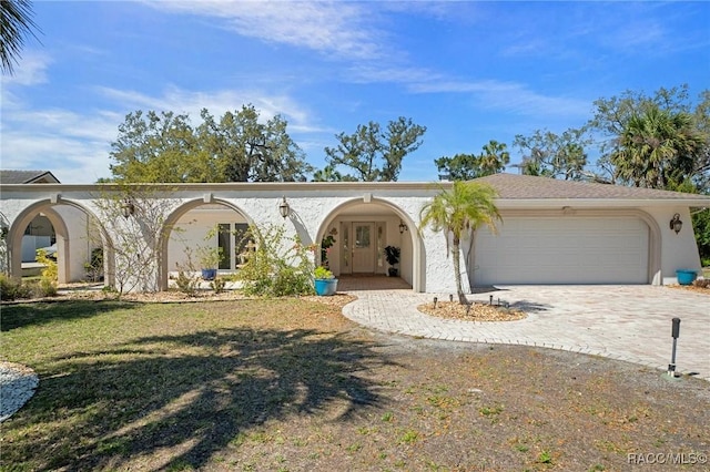 view of front of property with a garage, a front lawn, decorative driveway, and stucco siding