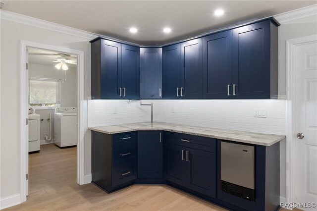 kitchen with blue cabinets, washer and dryer, light wood-style flooring, and light stone countertops