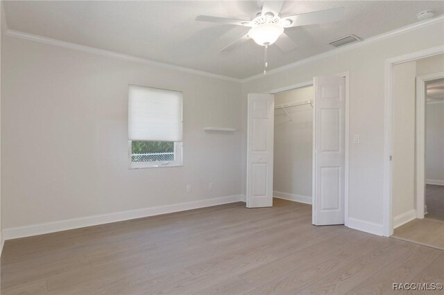 unfurnished bedroom featuring a closet, visible vents, ornamental molding, light wood-type flooring, and baseboards