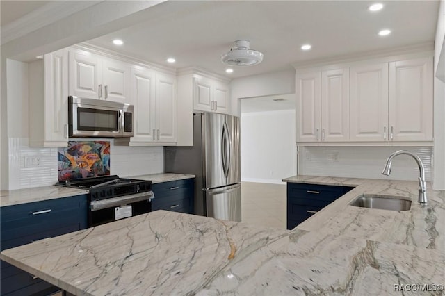 kitchen featuring light stone counters, a sink, white cabinets, ornamental molding, and appliances with stainless steel finishes