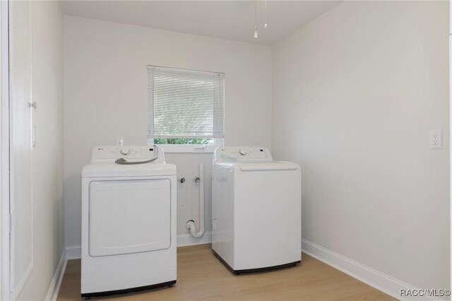 washroom with laundry area, baseboards, light wood finished floors, and washing machine and clothes dryer