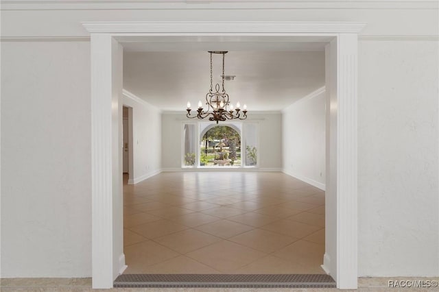 spare room with a chandelier, baseboards, tile patterned flooring, and crown molding