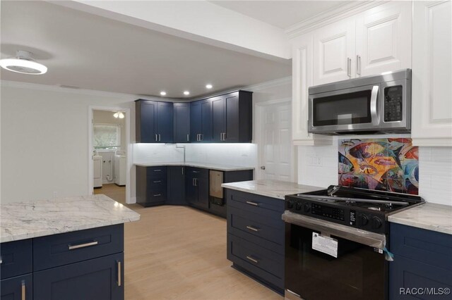 kitchen featuring ornamental molding, stainless steel microwave, independent washer and dryer, and black gas stove