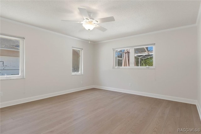 empty room featuring ornamental molding, light wood-type flooring, a ceiling fan, and baseboards