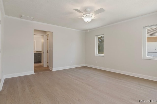 spare room with crown molding, ceiling fan, light wood-style flooring, and baseboards