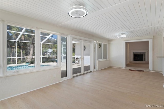 unfurnished sunroom with a fireplace with raised hearth and wood ceiling