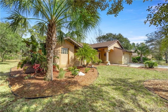 view of front of property with driveway, a garage, a front yard, and stucco siding