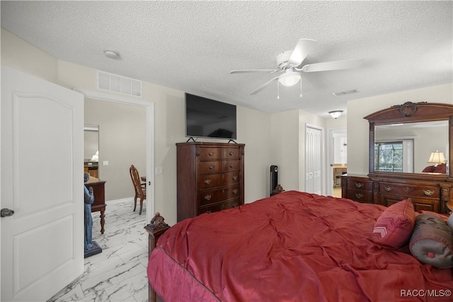 bedroom with marble finish floor, visible vents, and a textured ceiling