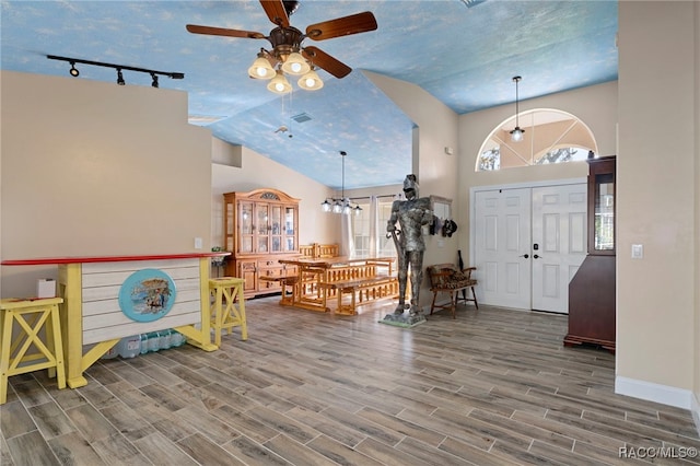 entryway featuring ceiling fan, rail lighting, and lofted ceiling