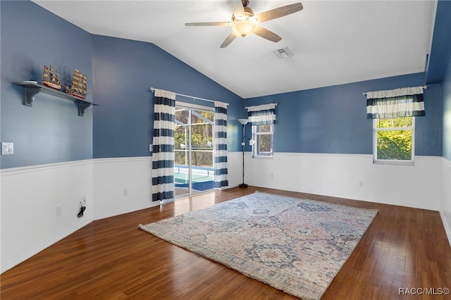 spare room featuring ceiling fan, a wealth of natural light, dark hardwood / wood-style floors, and vaulted ceiling