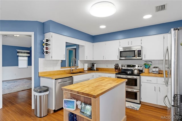 kitchen featuring appliances with stainless steel finishes, white cabinetry, sink, a kitchen island, and light hardwood / wood-style flooring