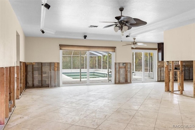 unfurnished living room with ceiling fan, light tile patterned floors, a textured ceiling, and a tray ceiling