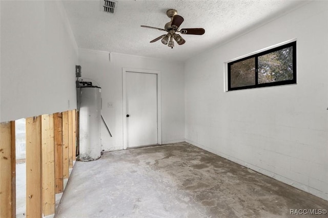 spare room featuring water heater, ceiling fan, concrete floors, and a textured ceiling