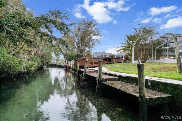 view of dock with a water view, a lanai, and a lawn