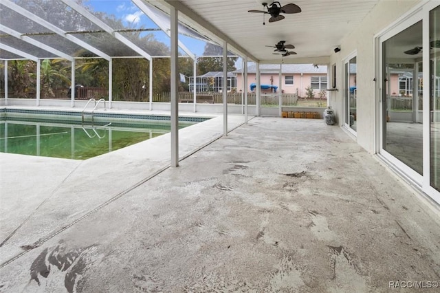 view of pool featuring glass enclosure, ceiling fan, and a patio