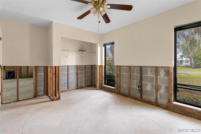 spare room with ceiling fan, light tile patterned floors, and tile walls