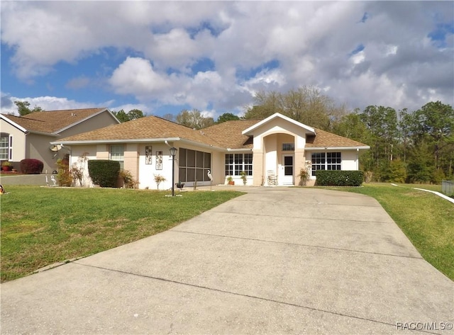 view of front of property with a front yard, concrete driveway, and stucco siding