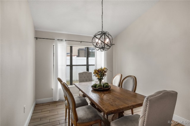 dining space with baseboards, a chandelier, and light wood finished floors