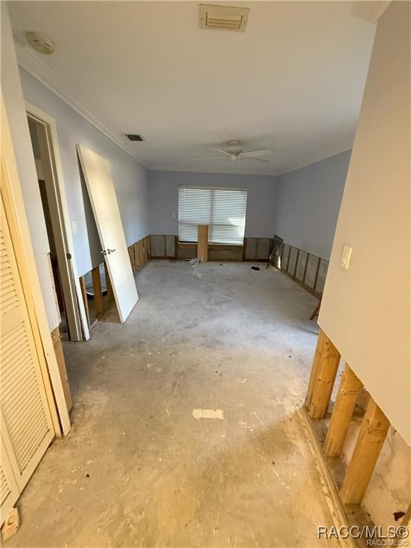 unfurnished room featuring ornamental molding, a ceiling fan, visible vents, and unfinished concrete floors