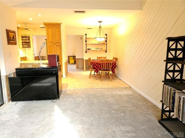 living area with wood walls, baseboards, visible vents, and concrete flooring