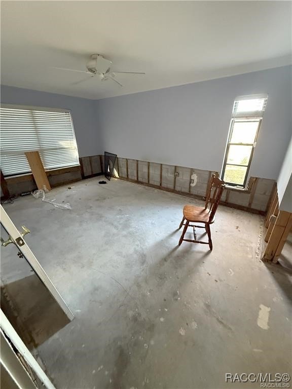 interior space with a ceiling fan and unfinished concrete floors