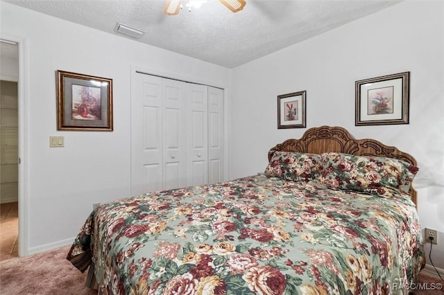 bedroom with a textured ceiling, carpet floors, visible vents, a ceiling fan, and a closet