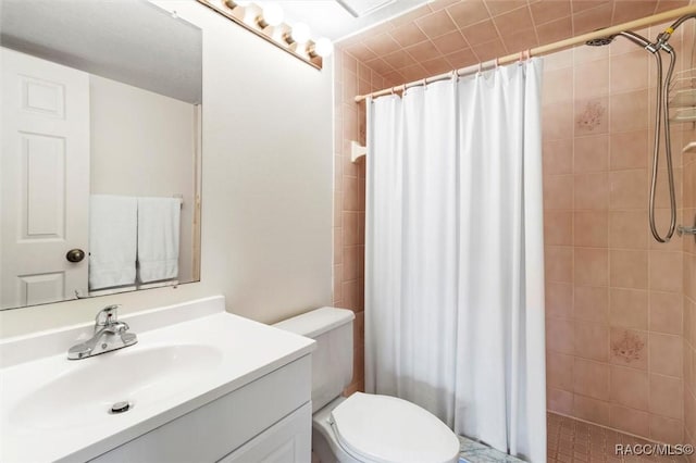 full bath with tiled shower, vanity, and toilet