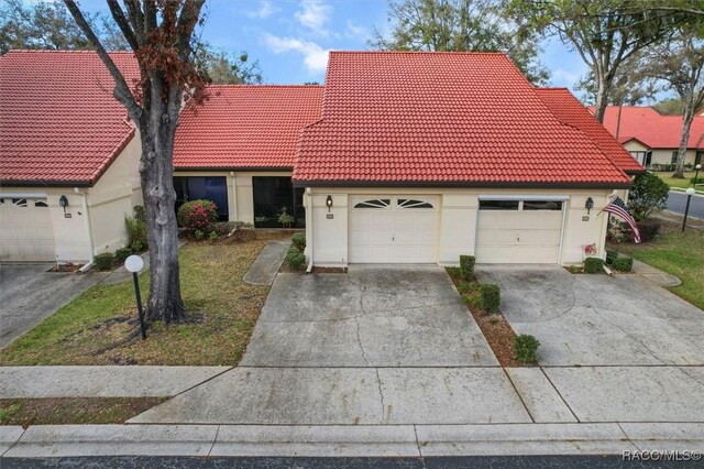 view of front facade featuring driveway, a tile roof, and stucco siding