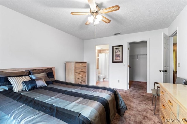 carpeted bedroom featuring visible vents, a walk in closet, a textured ceiling, and ensuite bathroom