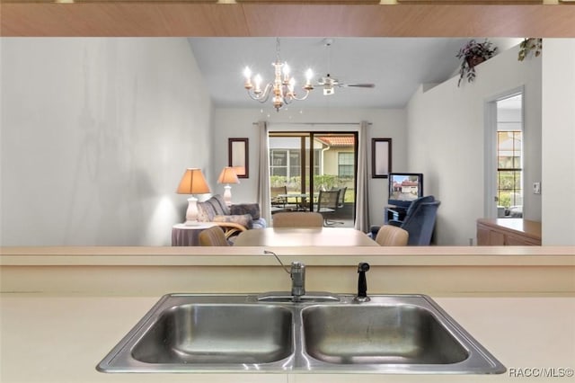 kitchen featuring lofted ceiling, open floor plan, light countertops, a chandelier, and a sink